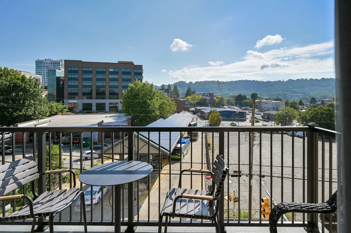 This exterior image captures a private balcony seating area overlooking Asheville’s cityscape with distant hills on the horizon. The tranquil atmosphere encourages guests to relax while taking in views of downtown, blending the excitement of urban exploration with moments of serene retreat.